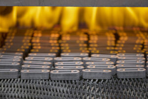 Small iron parts entering a sintering oven.